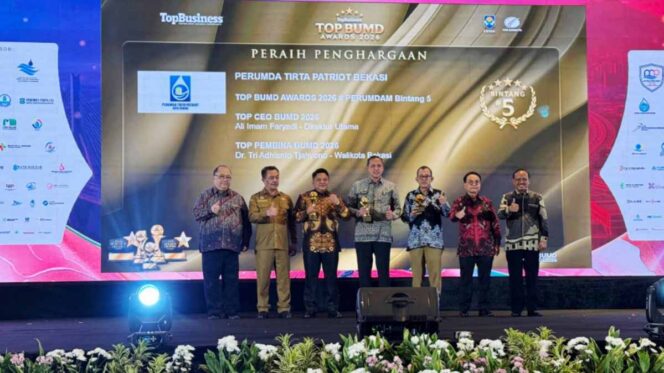 
					Direktur Perumda Tirta Patriot, Ali Imam Faryadi, saat menerima penghargaan di acara TOP BUMD 2026 bersama Wali Kota Bekasi